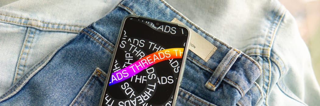 Tver, Russia - July 15, 2023, the threads logo on the smartphone screen lying on the jeans. The threads icon. The logo of the current application. Threads social network