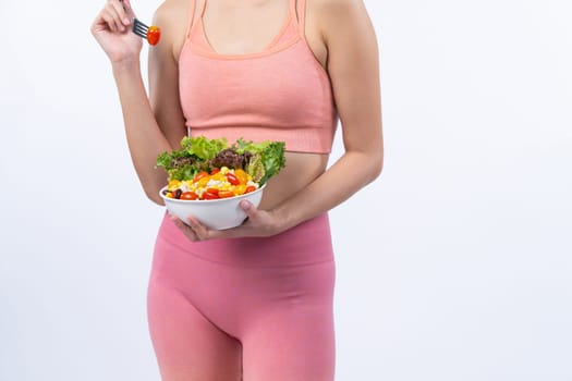 Young sporty Asian woman in sportswear holding salad bowl fill with vibrant of fruit and vegetable. Natural youthful and fit body lifestyle with balance nutrition on isolated background. Vigorous