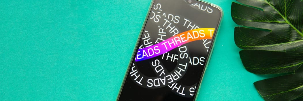 Tver, Russia - July 15, 2023, threads logo on the smartphone screen, on a green background. The threads icon. The logo of the current application. Threads social network