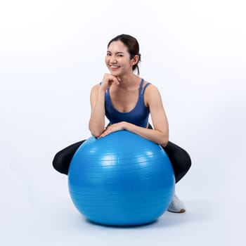 Young attractive asian woman portrait in sportswear with fit ball targeting on abs muscle for effective energetic daily workout routine. Studio shot and isolated background. Vigorous