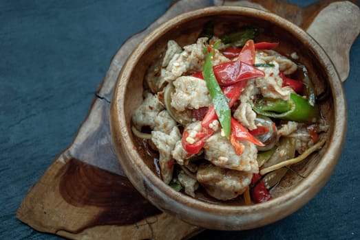 Thai Spicy food, Spicy stir fried fish balls and thai herbs vegetables in wooden bowl : in Thai language called "Pad Cha " Oblique view from the top.