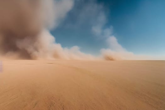 A desert scene with a large cloud of dust in the distance. The sky is clear and blue