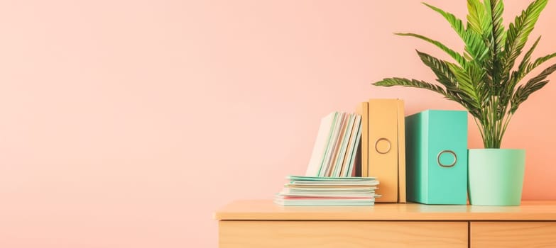 Colorful office supplies, binders, and a potted plant create a cheerful workspace on a wooden desk against a pink wall