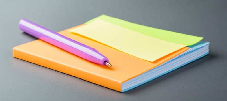 Purple pen lies on an orange notebook with colorful sticky notes, ready for taking notes or writing