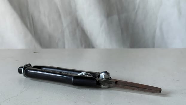 A metal compass is placed on a white surface, highlighting its design and functionality.