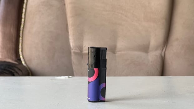 A colorful lighter is positioned centrally on a plain table in a warm, inviting space.