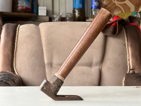 A hand tool with a wooden handle rests on a table in a workshop setting.