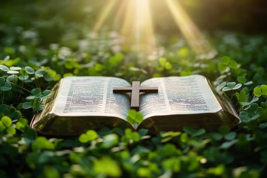 a bible book and a cross lying on the green clover leaves..