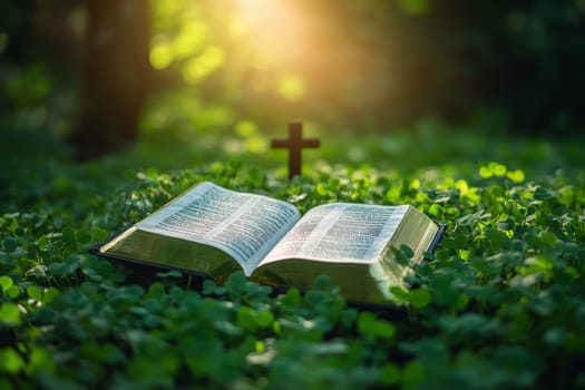 a bible book and a cross lying on the green clover leaves..