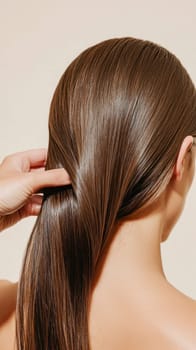 Back view of a woman touching her perfect straight, shiny, brown hair