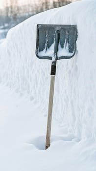 Snow shovel stuck in deep snow after blizzard, illustrating the challenge of snow removal