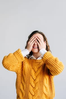 Young adult smiling beautiful positive woman model closing eyes covering with hands feeling anticipation. She is waiting for a surprise or gift, guessing a secret, isolated against a white background.