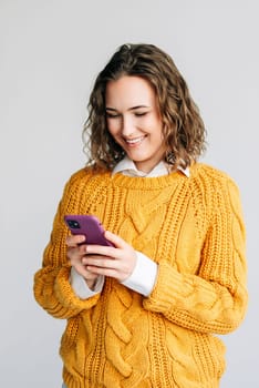 Smiling Woman Using Smartphone. A joyful young woman with curly hair using a smartphone. Ideal for depicting modern communication, technology, or social media themes. Isolated on a white background