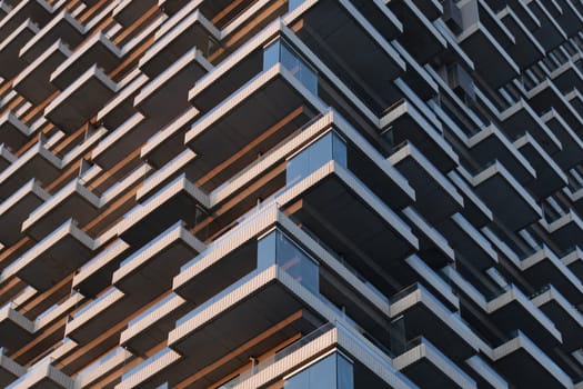 A close-up view of an architectural facade showcasing intricate balcony arrangements in a repeated pattern. The design elements highlight the building s modern structure and urban appeal, offering a strong geometric visual suited for architectural themes.