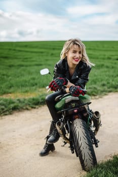 Woman in Leather Jacket Sitting on Motorcycle. Confident woman seated on motorcycle, wearing black leather jacket and gloves, with a focused look. Scene captures a sense of adventure