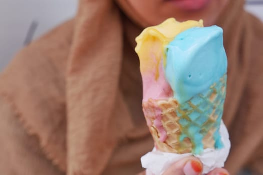 A vibrant ice cream cone featuring blue, pink, and yellow scoops, perfect for summer.