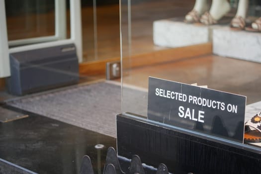 A sign showcasing selected products on sale at a retail store entrance, inviting shoppers