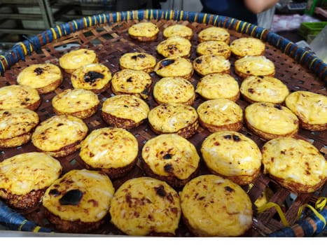 A basket filled with freshly baked Kue Lumpur Sidoarjo. The golden-brown cakes are arranged neatly, with a hint of a savory filling visible. The warm, inviting aroma fills the air.
