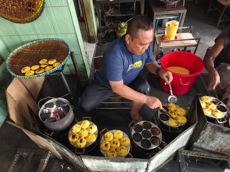 November 2, 2024. Sidoarjo, Indonesia. A man meticulously prepares and cooks iconic kue lumpur, a delectable treat known for its soft, molten center and crispy outer layer.