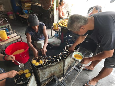 November 2, 2024. Sidoarjo, Indonesia. A man meticulously prepares and cooks iconic kue lumpur, a delectable treat known for its soft, molten center and crispy outer layer.