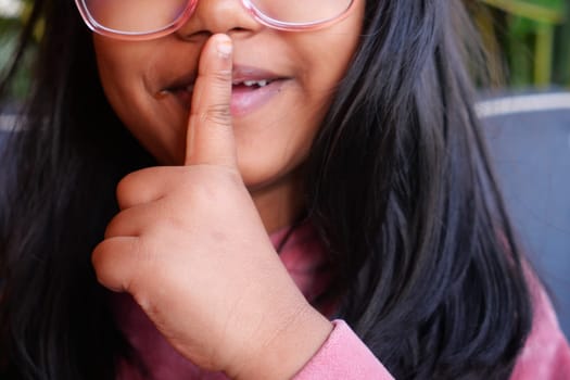 kid raising her hand indicating to stop talking or to be silent .