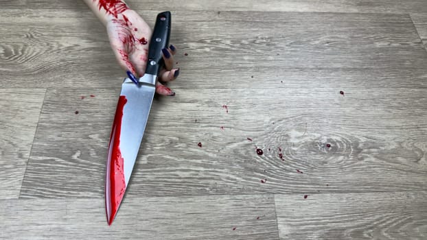 Bloody kitchen knife in hand of girl lying on floor with traces of blood. Domestic violence and use of weapons to commit crime. Knife murder investigation