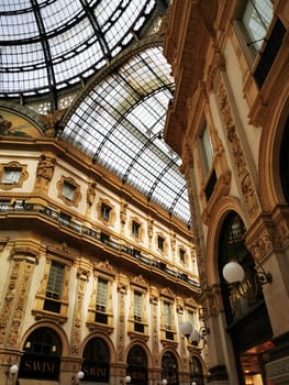 Visitors admire the intricate details of the beautifully designed Galleria Vittorio Emanuele II, showcasing stunning architecture and a majestic glass dome in Milan.