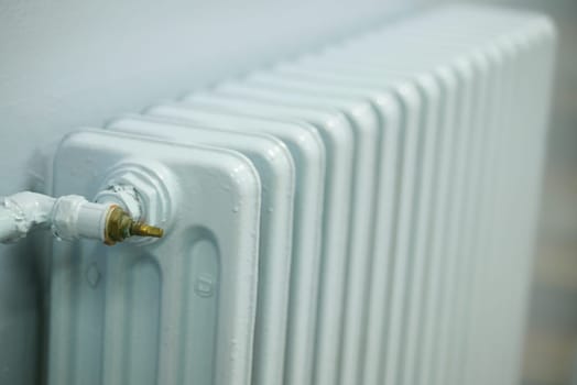 blue radiator on grey white wall. apartment heating installation system