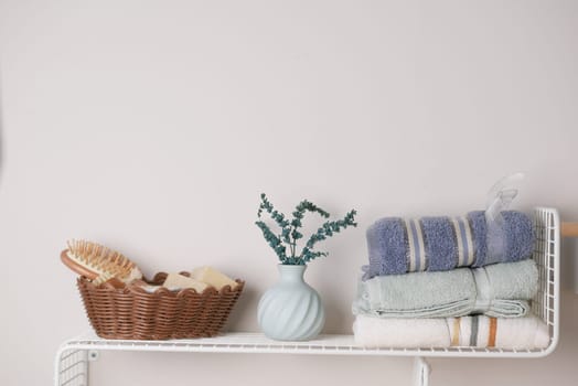 A chic bathroom shelf with neatly arranged towels, a vase, and elegant natural decor accents