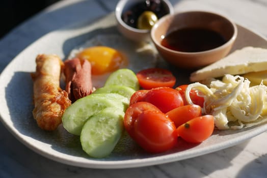 A vibrant breakfast platter featuring fresh vegetables, olives, and dipping sauce.