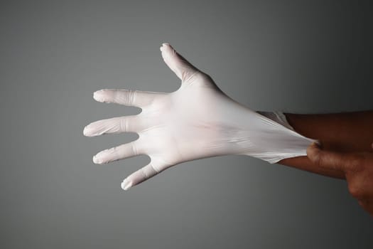 A hand carefully putting on a latex glove in a clinical setting, ensuring sterility and protection
