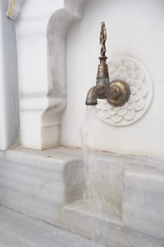 A stunning and beautiful marble water fountain that features an elegant brass spigot