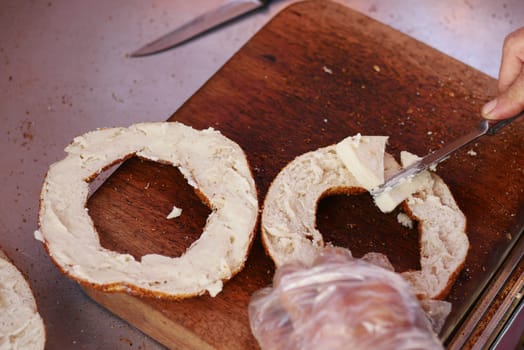 spreading butter on Turkish Bagel Simit on table ,