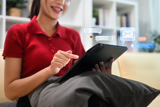 Smiling young woman using digital tablet with with social media notifications bubbles surrounding.