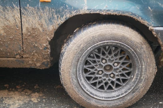 Closeup of a muddy, weathered wheel on an old classic car, highlighting its rugged design