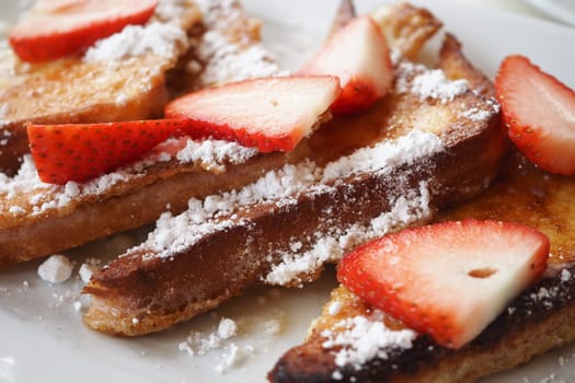 A mouthwatering plate of delicious French toast topped generously with fresh, ripe strawberries