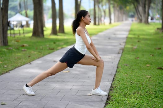 Young sporty woman in activewear warming up before jogging.