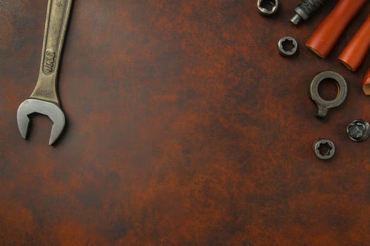 A collection of vintage tools including a wrench and various nuts on a rich brown leather background, perfect for workshop themes and DIY projects.