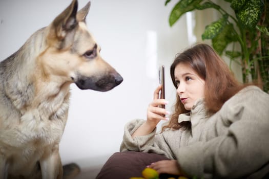 A woman comfortably engages with her German Shepherd in a relaxed indoor setting, enjoying quality time together.