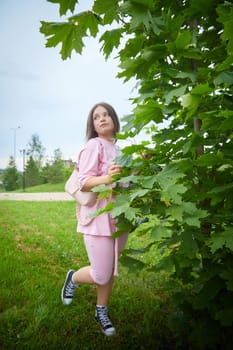 Portrait of young nice pretty woman with long brown hair in greenery