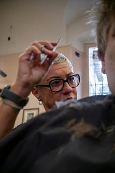 Cremona, Italy - November 27th 2024 Hairdresser cutting hair of customer in barbershop in cremona, italy