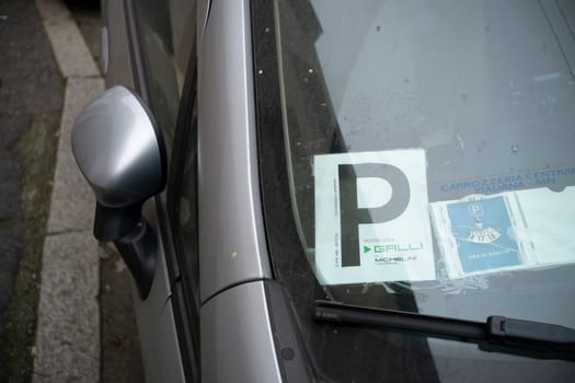 Cremona, Italy - November 27th 2024 Learner driver permit and parking disc visible on a car windshield, showcasing italian driving regulations and parking practices