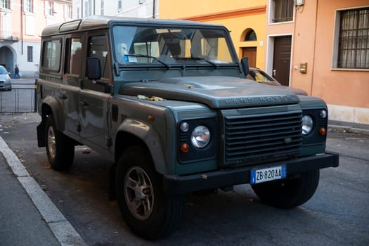 Cremona, Lombardy, Italy - October 27th 2024 Green land rover defender 110 station wagon parked on the side of a street in an urban setting