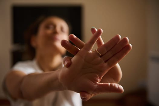 A woman performing a yoga pose indoors, focusing on hand movement for balance and mindfulness. The serene atmosphere emphasizes relaxation and mental clarity during her practice.