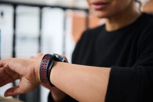 A close-up of a woman checking her smart wristwatch, emphasizing technology and fitness. The smartwatch features a stylish design, highlighting health monitoring and modern lifestyle integration.