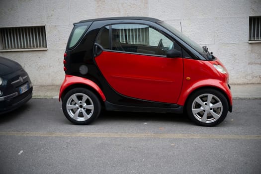 Cremona, Lombardy, Italy - October 27th 2024 A red and black smart fortwo coupe is parked on the side of a street, showcasing its compact size and two-tone design