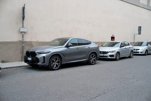 Cremona, Lombardy, Italy - October 27th 2024 Parked bmw x6 m competition, skyscraper metallic grey, v8 engine, 2021, next to a fiat tipo and a suzuki swift