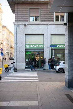 Cremona, Italy - November 27th 2024 Customers walking and waiting in line at a poke go restaurant in cremona, italy, with a delivery driver crossing the street