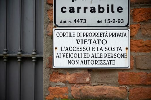 Cremona, Italy - November 27th 2024 Showing a weathered no parking sign in italian on a brick wall in cremona, italy, indicating private property and restricted access