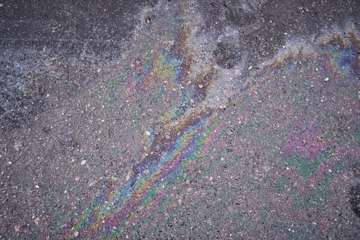 Rainbow stain from gasoline or oil leak on asphalt road
